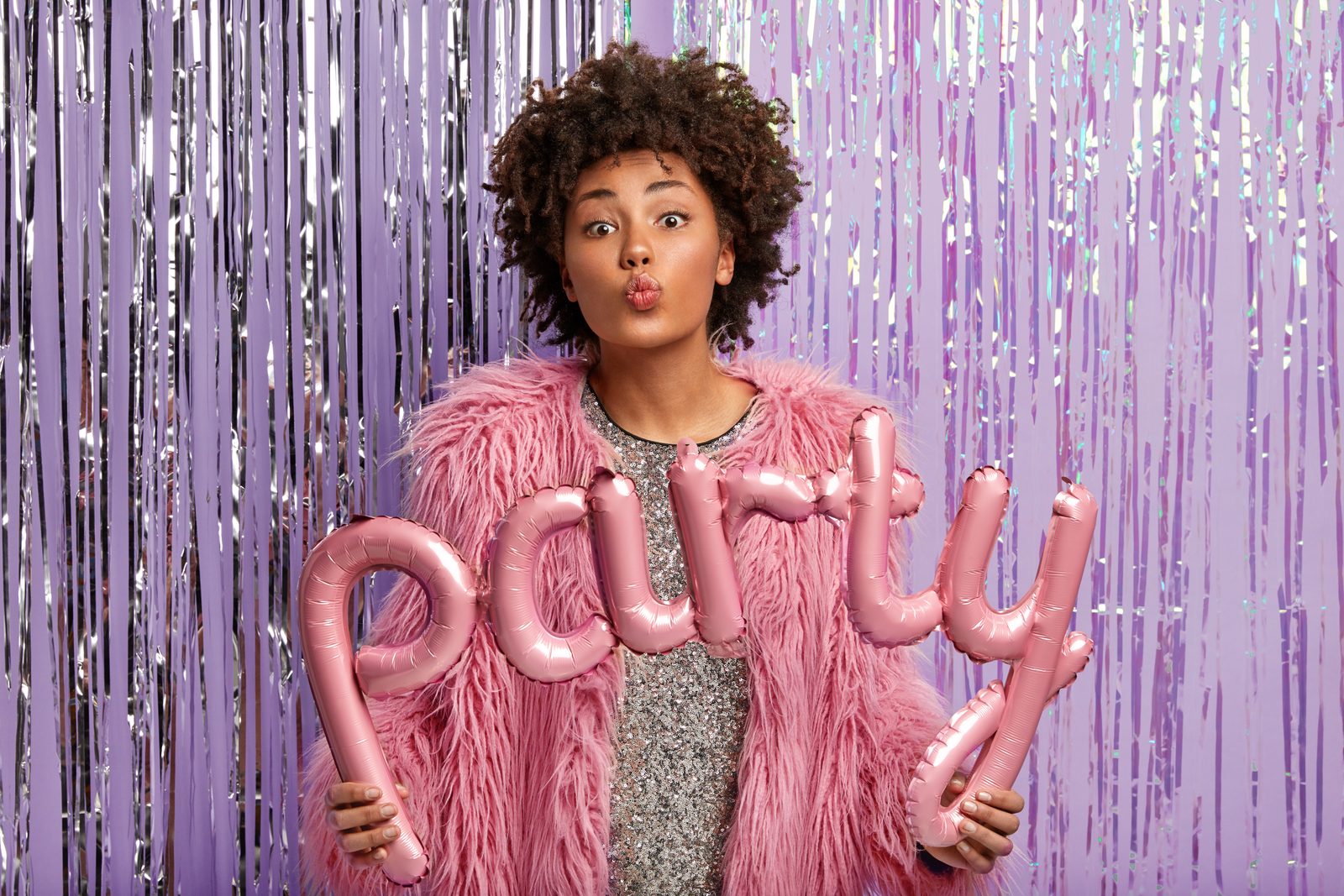 Guest holding party balloons in front of a photo booth backdrop